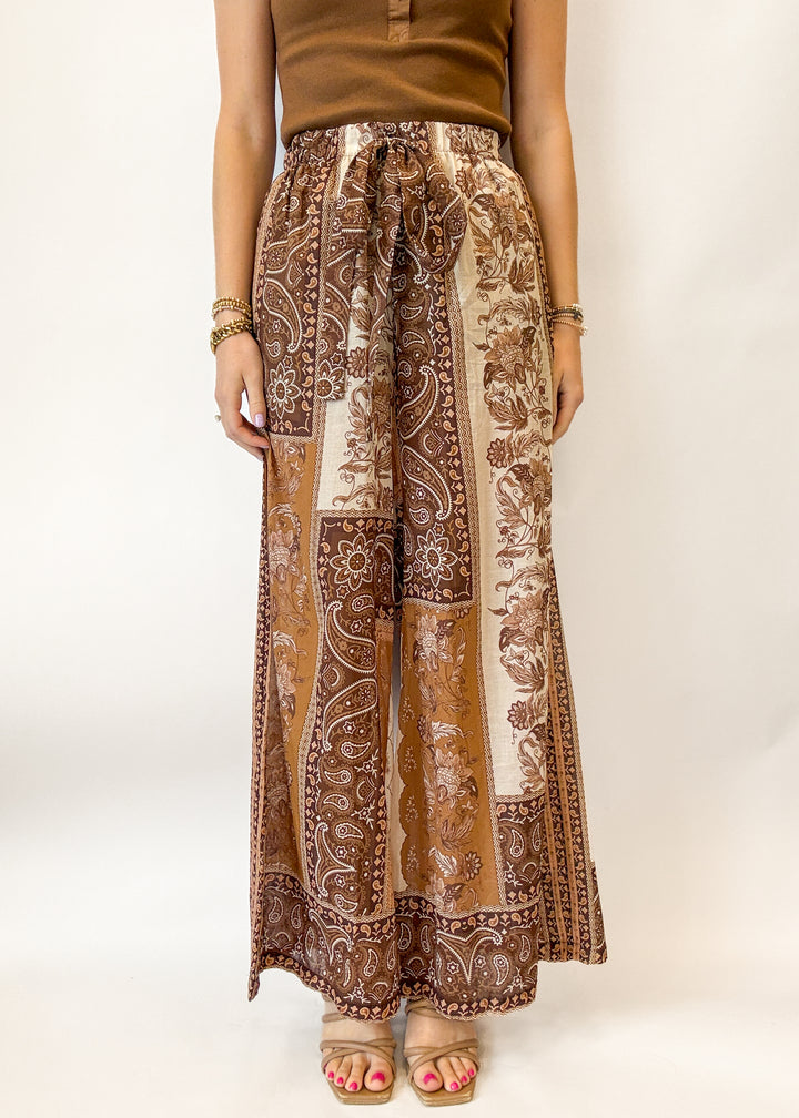 Person wearing brown patterned pants on a white background