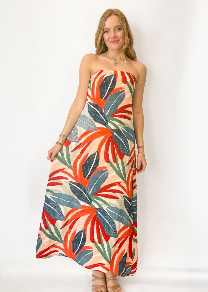 Woman wearing a strapless dress with a colorful leaf pattern on a white background