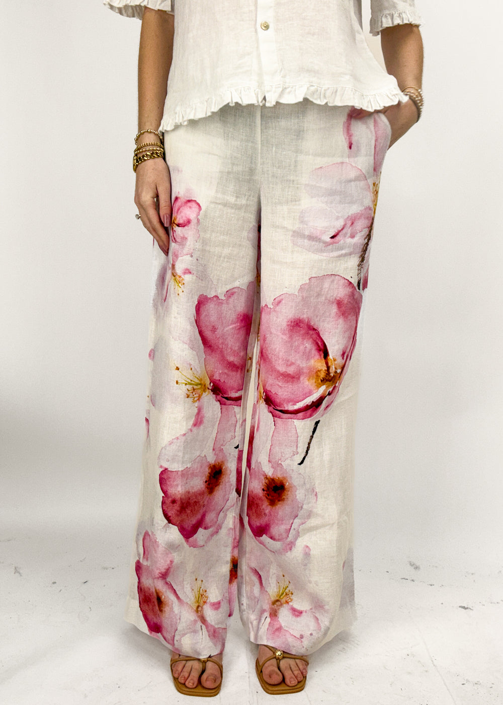 Person wearing floral pants with a white top on a white background