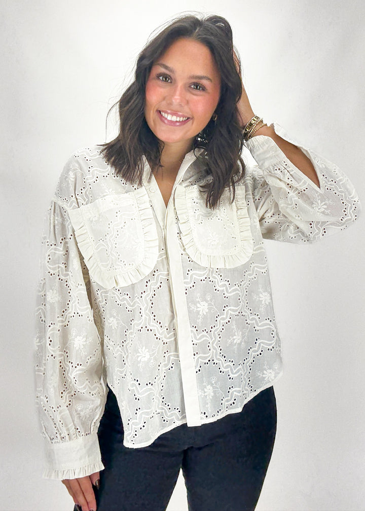 Woman wearing a white lace blouse against a plain background