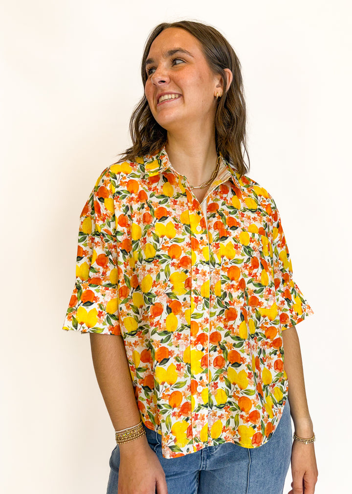 Woman wearing a colorful floral blouse against a plain background